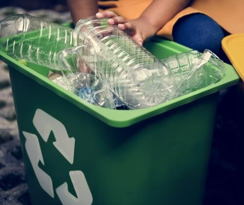 person putting plastic into recycling bin