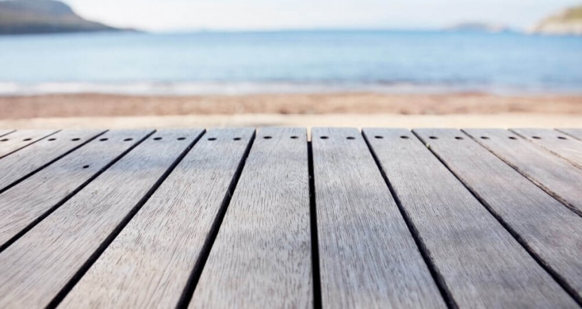 strip of decking overlooking a beach and blue skies