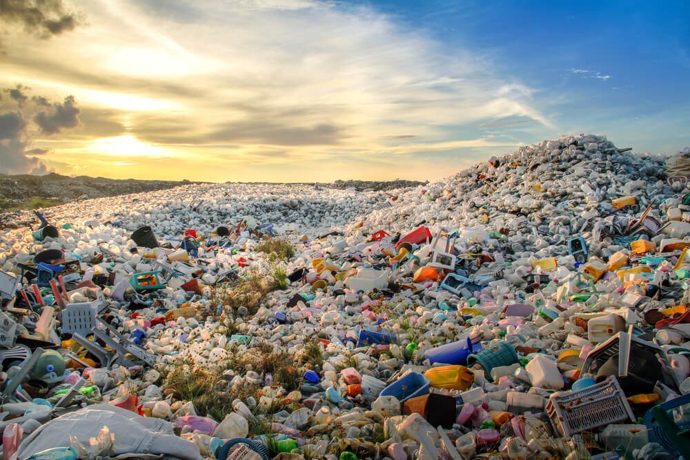 piled up waste at landfill site with sunset shining over