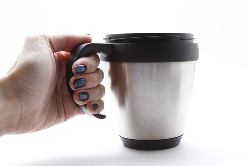 person holding silver thermal coffee mug